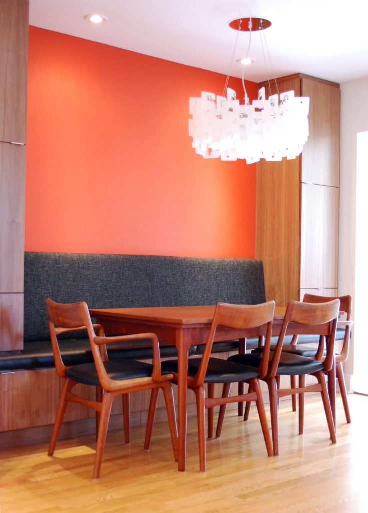 A bright orange wall pops against the charcoal gray banquette in this Ottawa, Ontario, kitchen