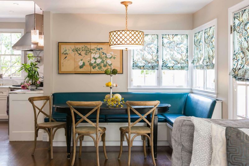 A custom peacock blue banquette, an Asian silk screen and peacock inspired Roman shades make for an elegant San Francisco kitchen nook