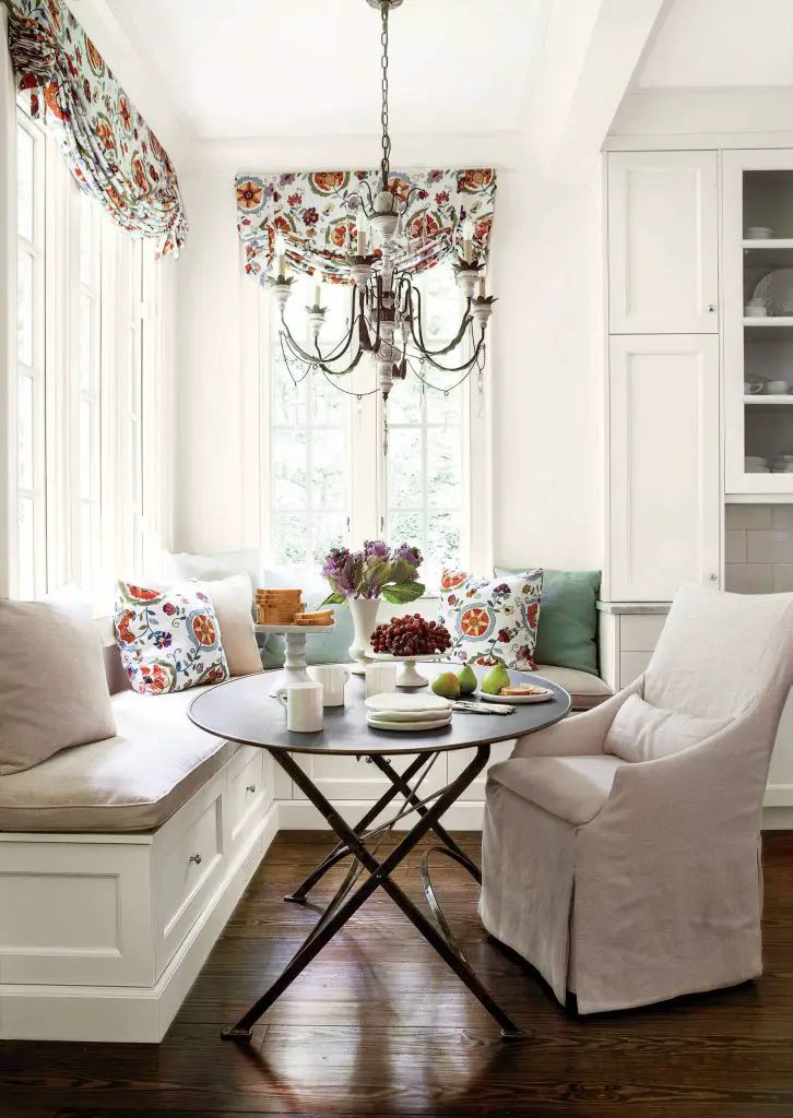 A linen covered banquette and armchair surround a metal bistro table in a traditional Atlanta kitchen