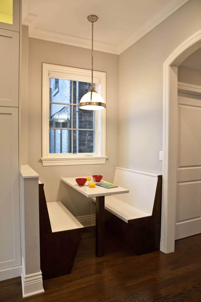 A stained maple post and white Silestone top were used to create the table for this minimalist breakfast banquette