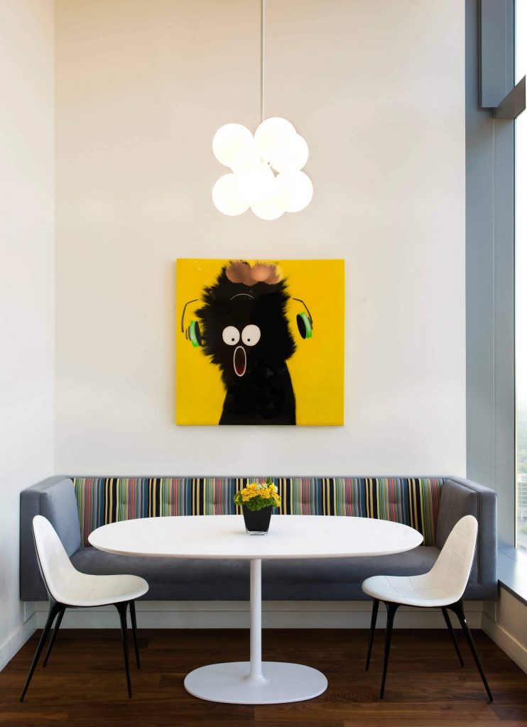 A white Drizzle table from Arper and comical cat inspired art make for a festive breakfast nook in this Austin, Texas, kitchen