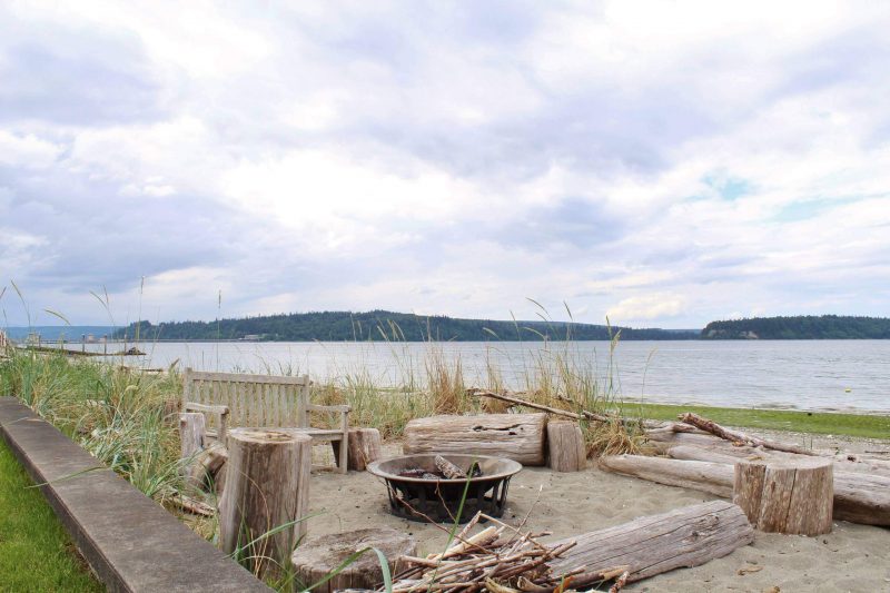 Casual fire pit area sits right off a lawn and deck