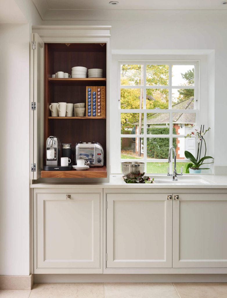 This renovated kitchen in the English countryside by Davonport features a custom cabinet with a pullout coffee shelf. The warm wood inside the cabinet provides a nice contrast to the taupe exterior.