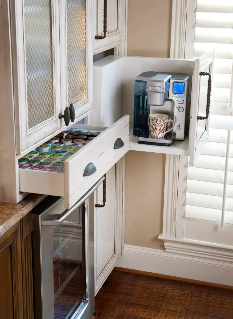 A drawer in this Dallas kitchen by LGB Interiors is the perfect height to store the coffee maker, while a shallow pullout drawer to the left is ideal for storing coffee pods.