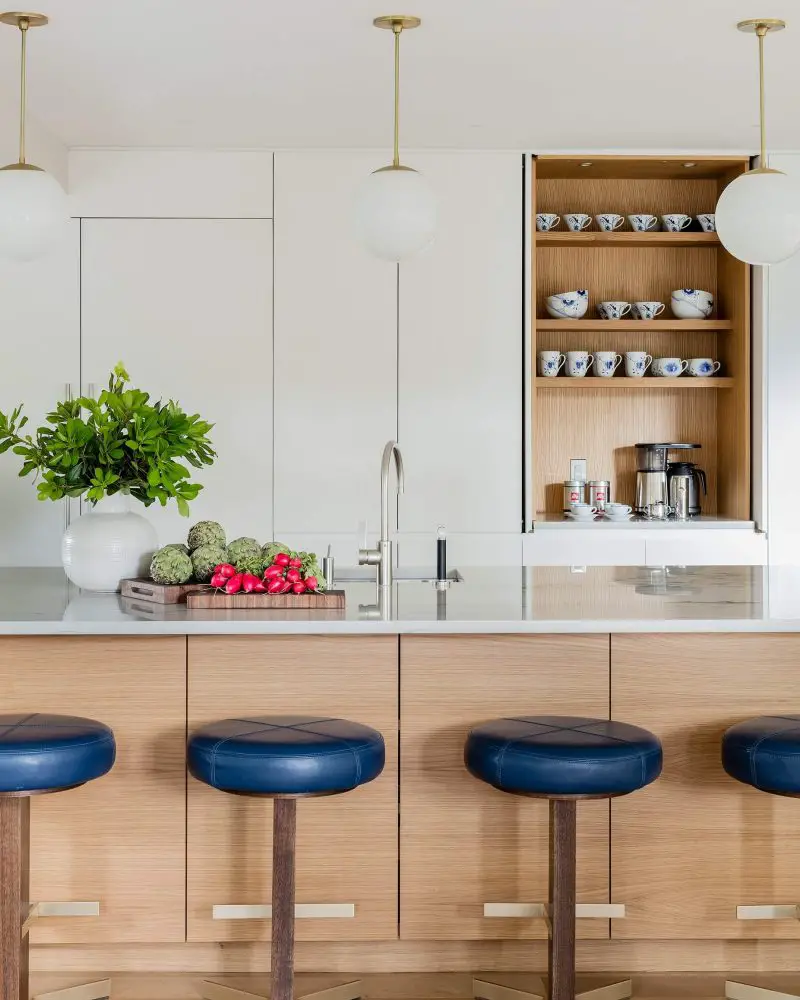 All of the appliances are hidden behind cabinets in this contemporary Boston kitchen by Mandarina Studio. One of the cabinets opens to reveal a wood-lined coffee station with loads of storage.