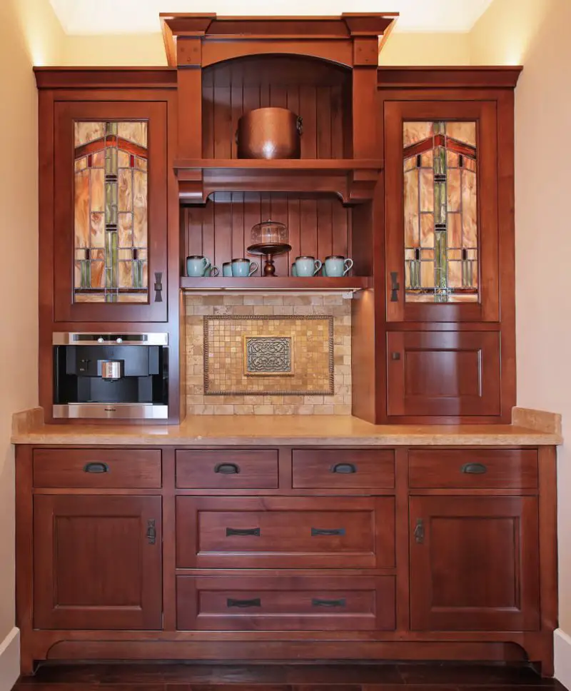 A built-in coffee maker adds a convenient and modern touch to this Craftsman-style built-in cabinet with stained glass doors. This San Diego kitchen was designed by Studio 6 Architects.