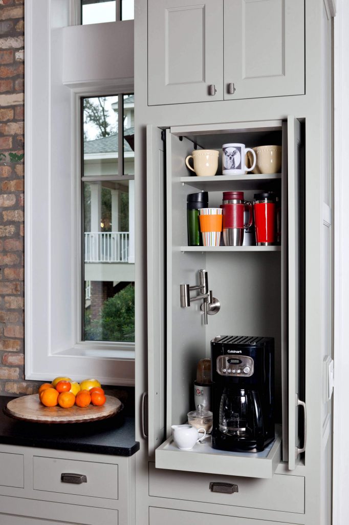 Pocket doors open to reveal a coffee maker atop a pullout shelf here. Note the water tap, which allows someone to fill the coffee maker without having to move it. Space was designed by In Detail Interiors.