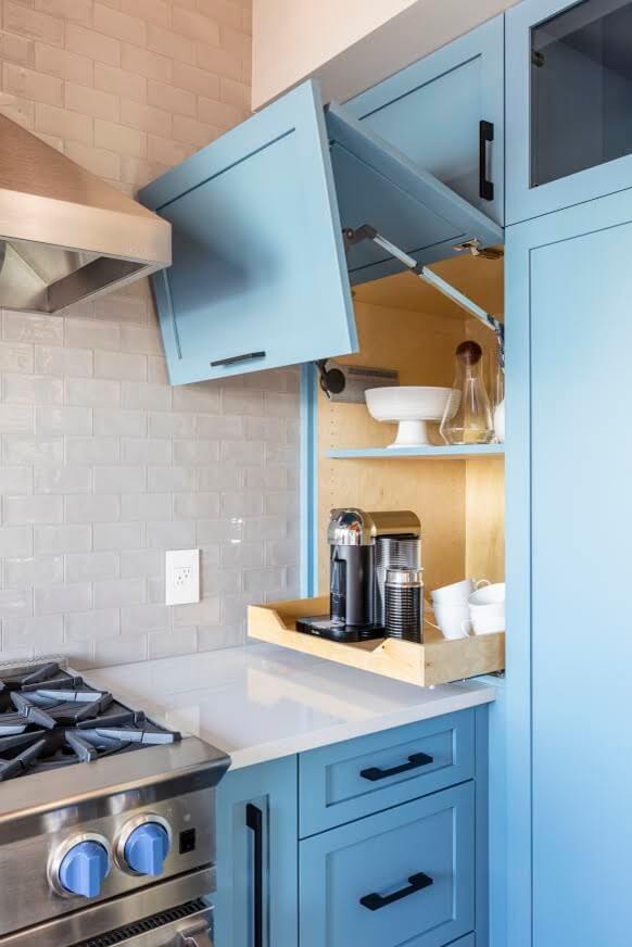 Interiors by Popov made the most out of every inch of this Seattle kitchen by adding a small appliance garage to an awkwardly shaped corner. The cabinet door lifts to reveal a coffee maker on a pullout shelf.