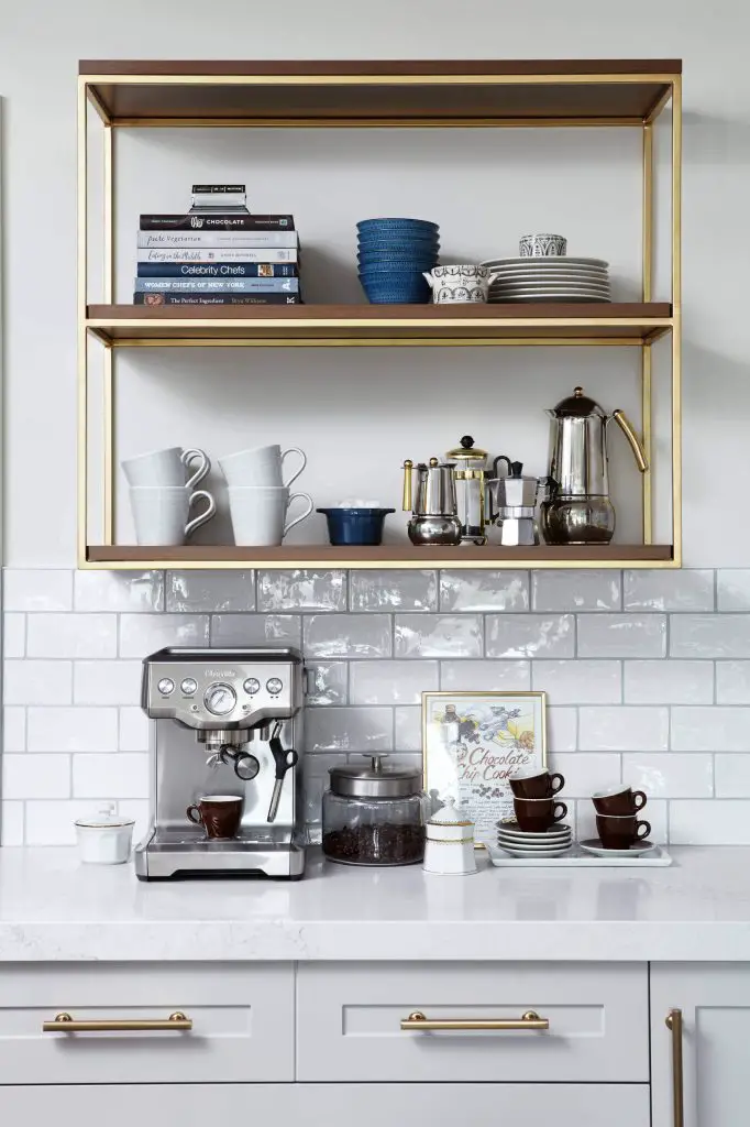 A walnut-and-brass shelving unit above the coffee maker here makes for a stylish place to store coffee mugs and coffee and espresso makers. The glossy subway tile backsplash is another nice touch. This Toronto kitchen was designed by Orsi Panos Interiors.