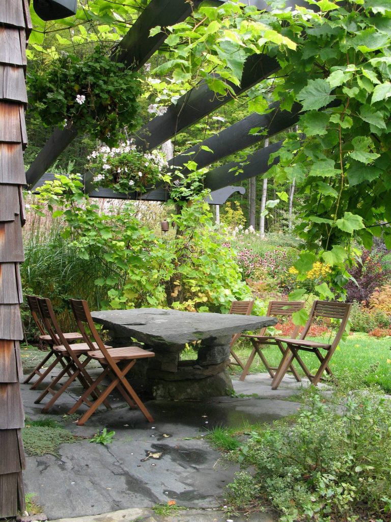 Example of a small classic backyard stone patio design in Burlington with a pergola