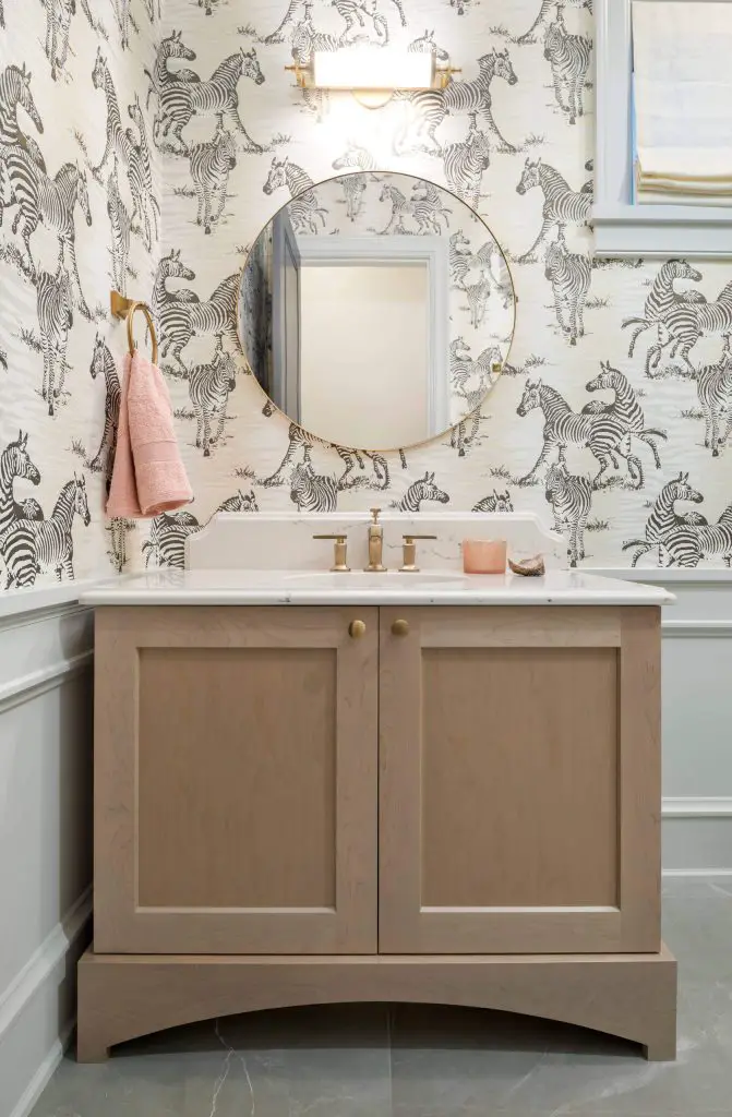 Wallpaper featuring playful zebras, a light wood custom vanity, and gray marble floors are among the highlights of this Vancouver powder room designed by Magpie Interiors.