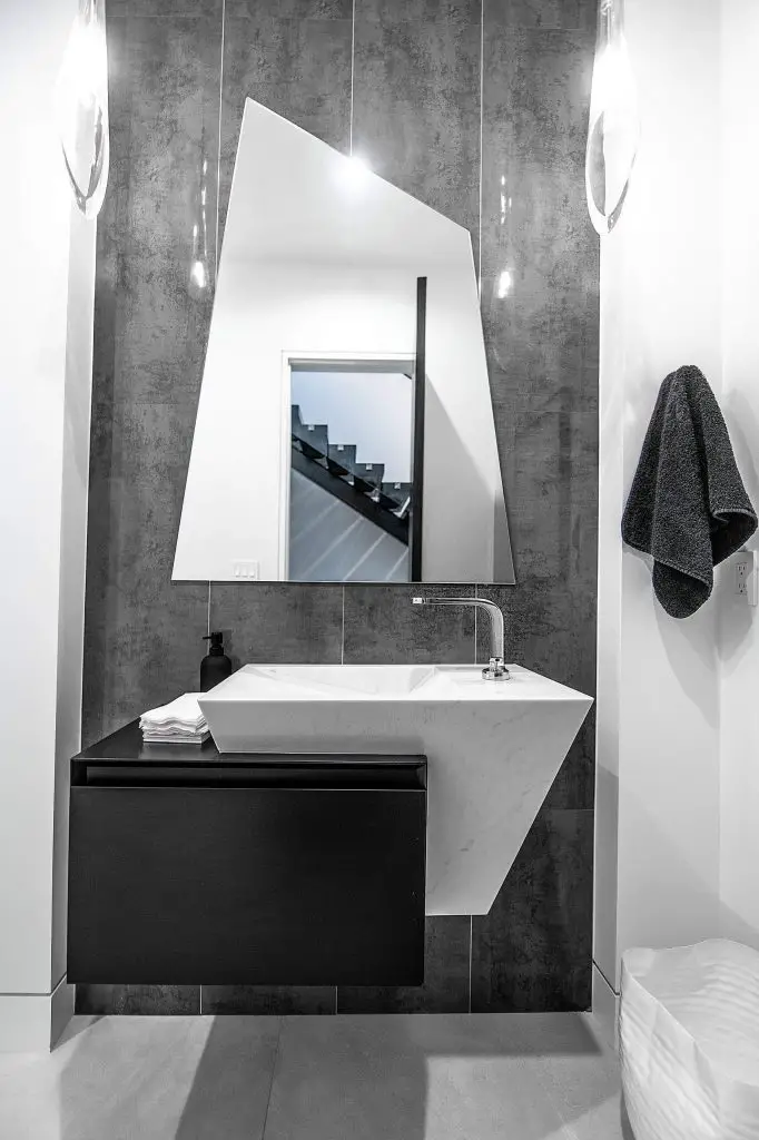 The design team at Pedini Los Angeles had the wall mirror cut into a trapezoid to mimic the shape of the vanity in this stylish Los Angeles powder room.