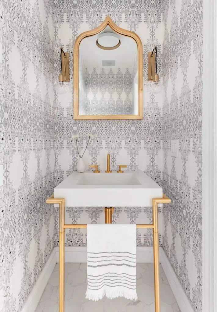 The wallpaper, towel, and gold mirror create a Moroccan vibe in this trendy Manhattan powder room.