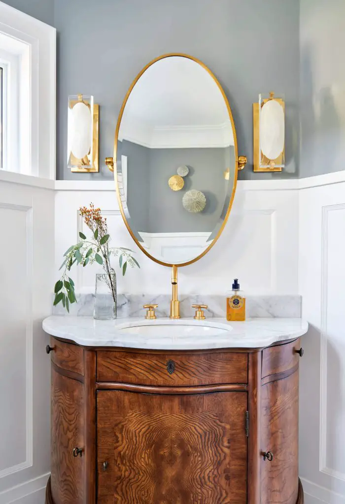 The wainscoting, brass sconces and antique dresser transformed into a vanity create an elegant powder room in Toronto, by Diana Bastone Designs.