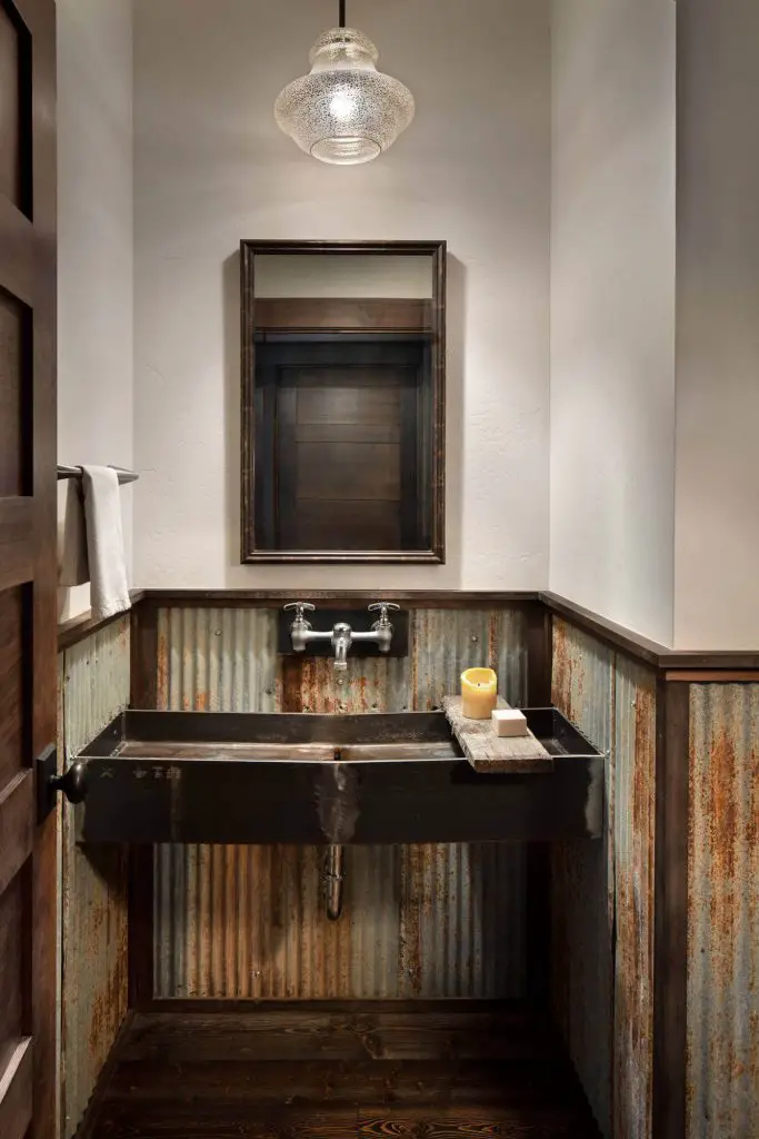 A salvaged metal sink and corrugated metal walls add rustic appeal to this Montana powder room built by Denman Construction.