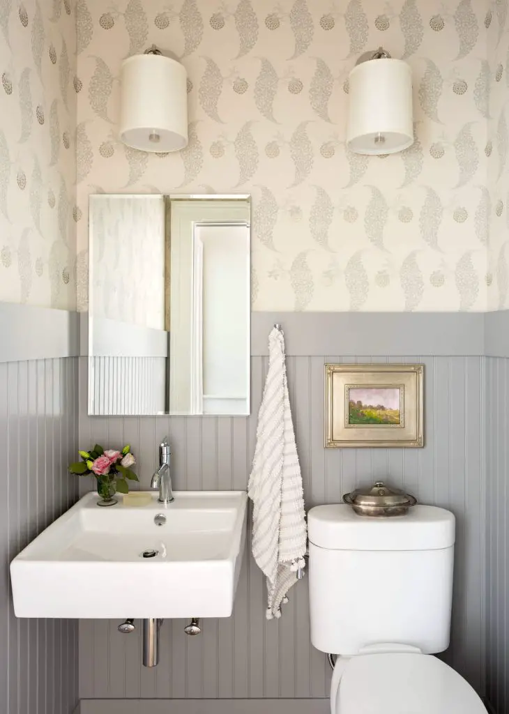C. Kramer Interiors added a lot of nice design touches to make this Connecticut powder room shine. Note the gray painted wainscoting, the linen wall sconces, and the perfectly sized painting above the loo.
