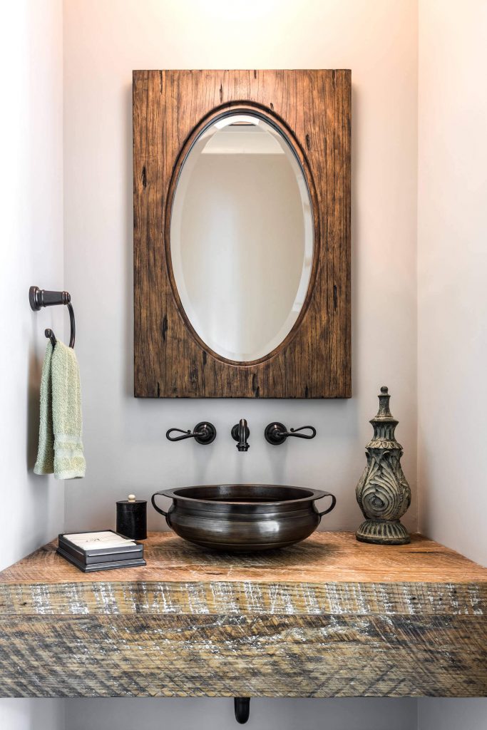This Zen-like powder room in South Carolina was built by Dillard-Jones Builders. It features a dark bronze vessel that has been transformed into a sink. The vanity base is made of reclaimed wood.