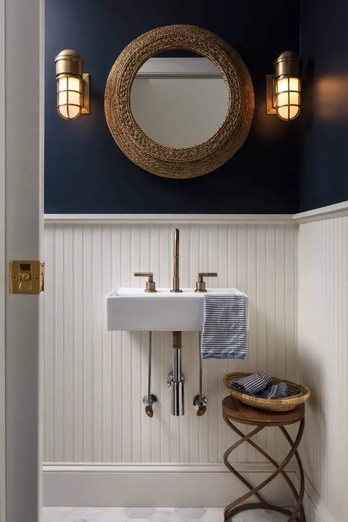 This nautical-theme powder room in Westchester, New York, was designed by the M&P Design Group. It features nautical sconce lights, a rope mirror, and dark navy painted walls.