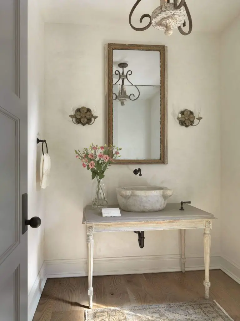 Plaster walls and a vanity that combines distressed wood and a stone vessel sink add Shabby Chic-style touches to this St. Louis powder room by Amy Studebaker Design.