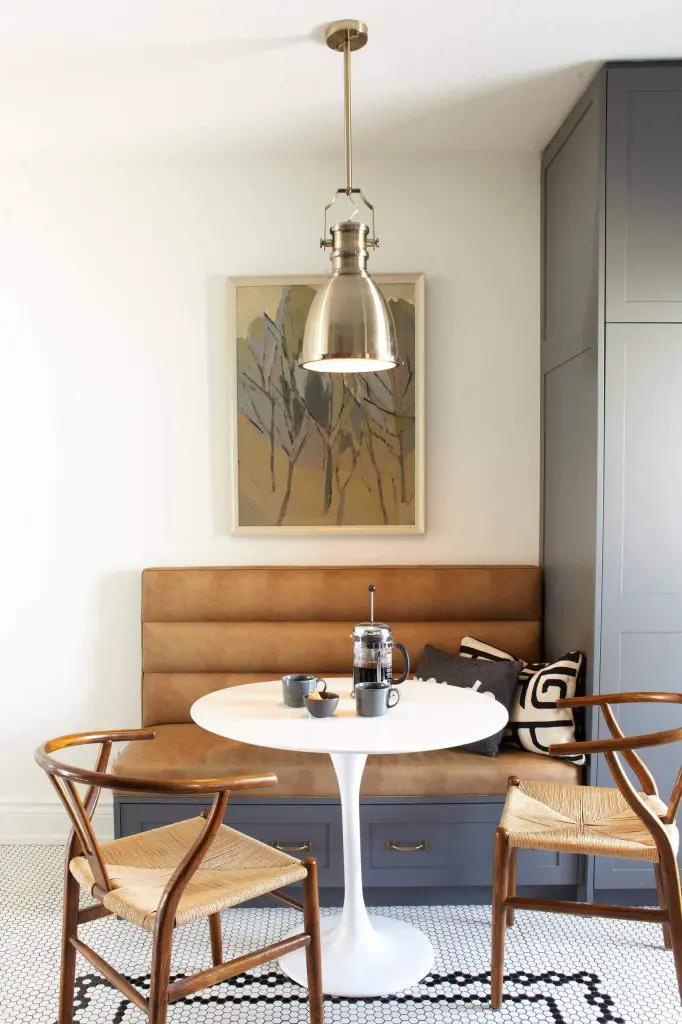 The black and white tile floor, distressed leather banquette and Wishbone chairs make for a handsome breakfast nook in Toronto