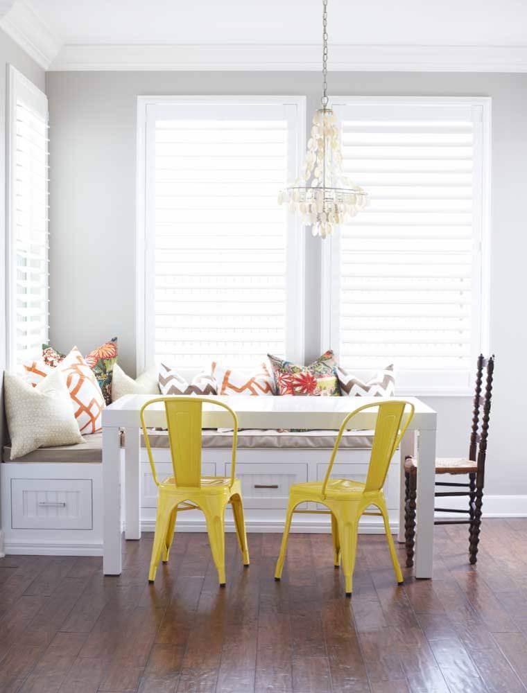 The bright yellow metal Tolix chairs make a bright splash in this otherwise neutral toned breakfast nook in San Diego