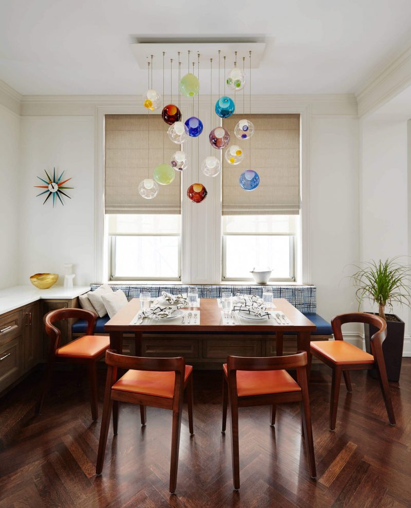 The colorful glass chandelier and Vitra Nelson Sunburst clock are highlights of this breakfast nook in Manhattan