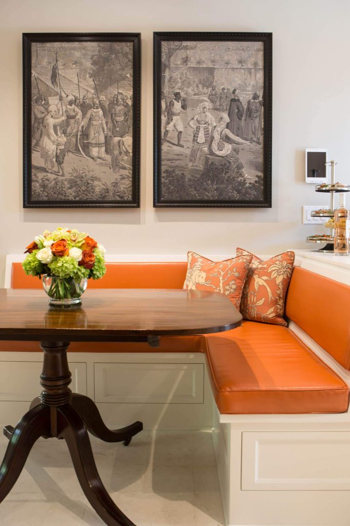 The orange faux leather covered banquette pops in this traditional kitchen breakfast area in Pasadena, California