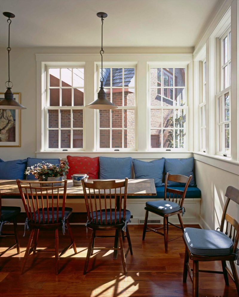 This traditional kitchen in Philadelphia has a collection of blue and red throw pillows lining the back of its built in banquette