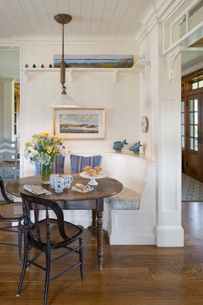 This white paneled breakfast nook in Providence, Rhode Island, features a curved banquette and an antique table.