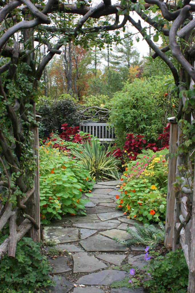 A custom arbor made from driftwood leads to a vegetable garden in New York.