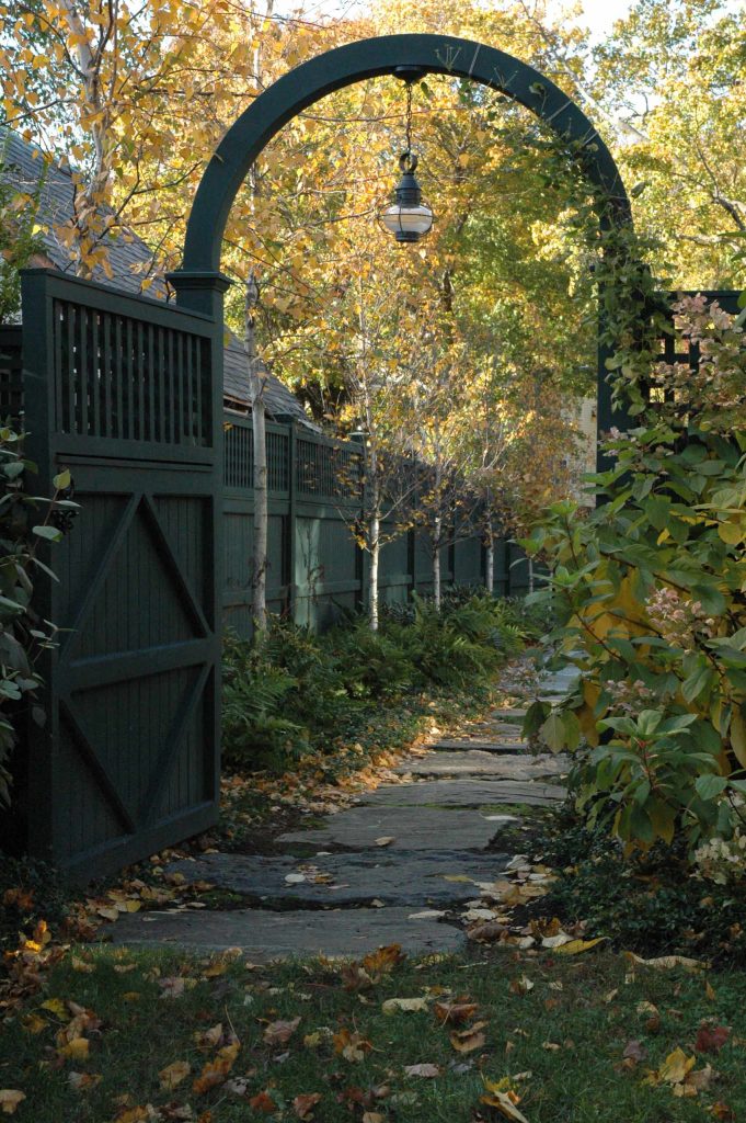 A forest green fence and gate made from cedar lead to this Boston garden