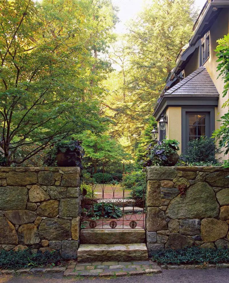 A former hunting lodge in the Boston area has an antique wrought iron gate that provides access from the driveway to the garden courtyard.