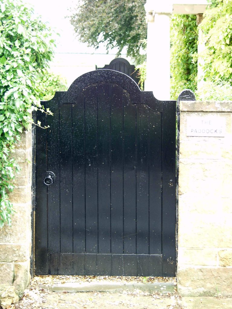 A hefty traditional garden gate is painted black and provides privacy for this garden in England.