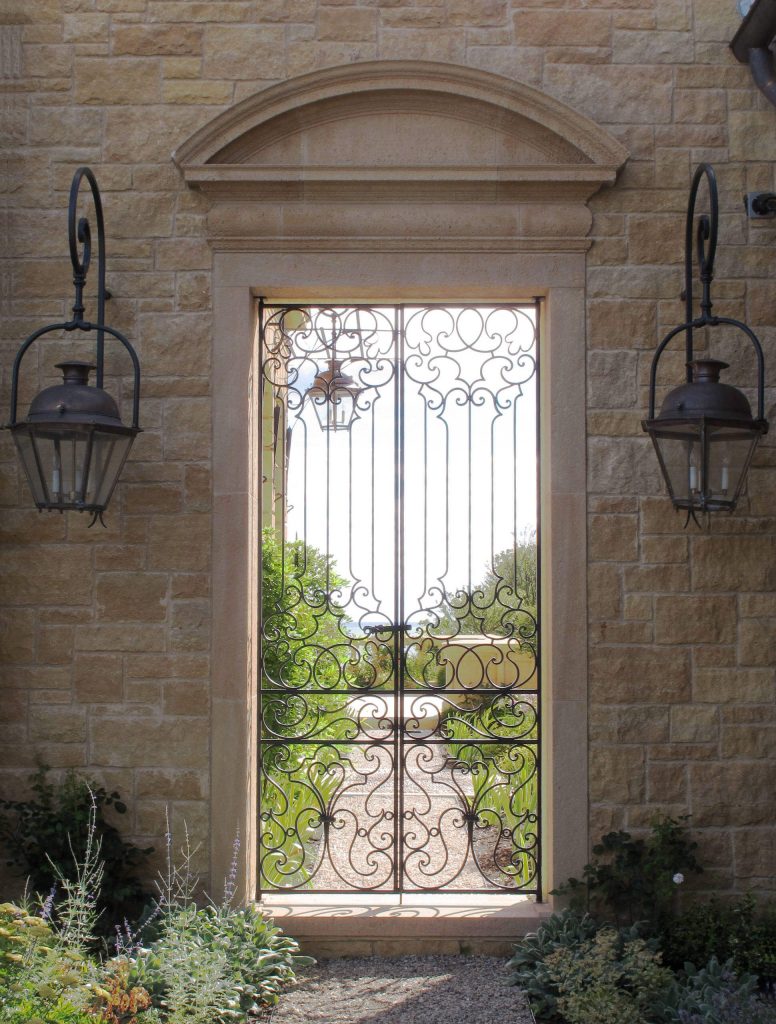 A large limestone wall with a thin iron gate provides views of Lake Michigan and a lovely garden in Chicago.