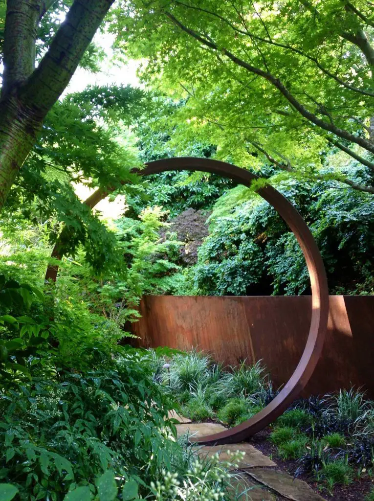 A large ring gate made from Cor Ten steel provides an eye popping entrance to this San Francisco garden