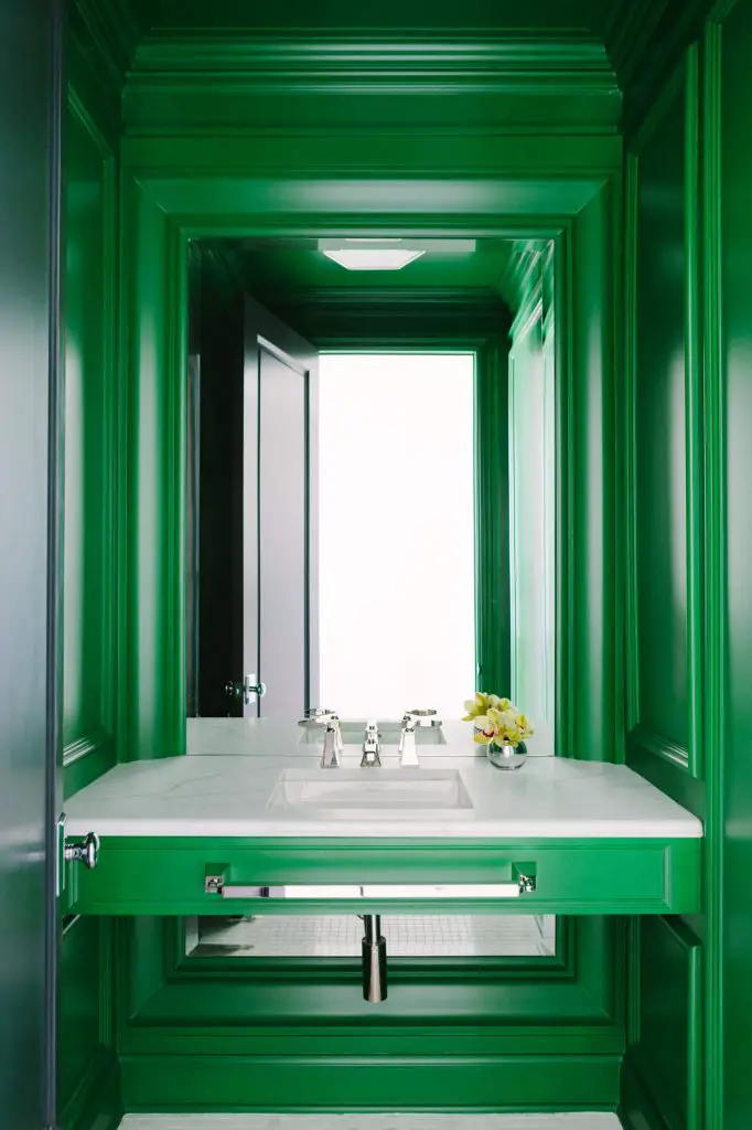 A rich green pops on a powder room’s vanity and millwork in a home by Randall Architects