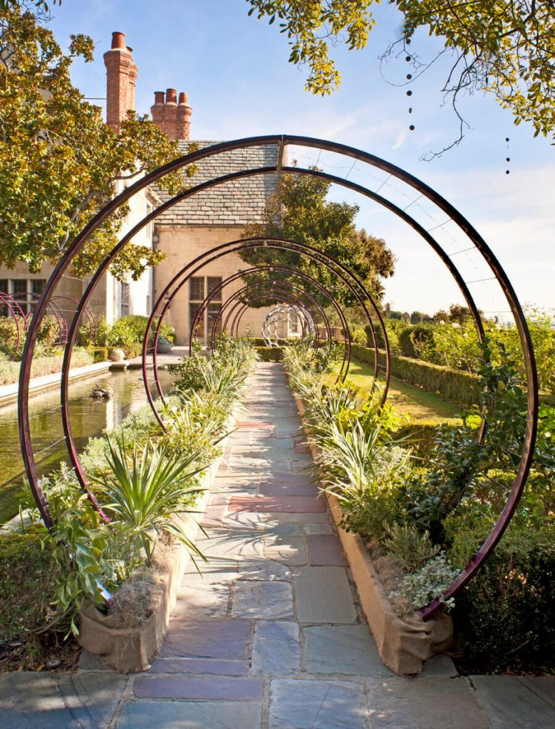 A row of 14 Gracie modern arbors next to a garden’s reflecting pool was imagined