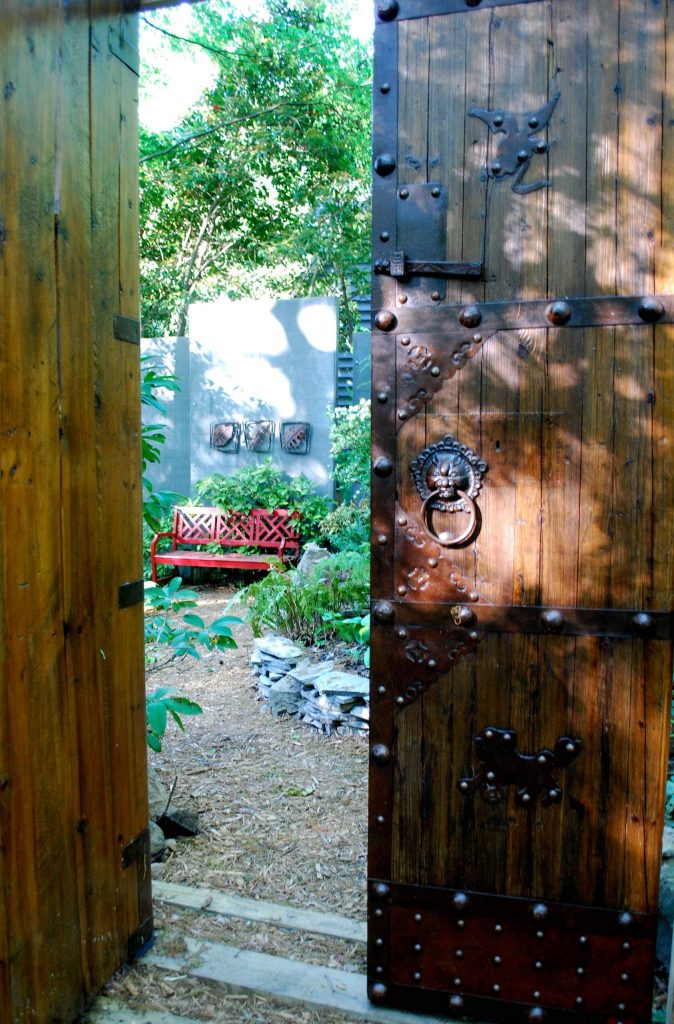 A set of Chinese doors marks the entrance to a hosta garden at the top of a koi pond.