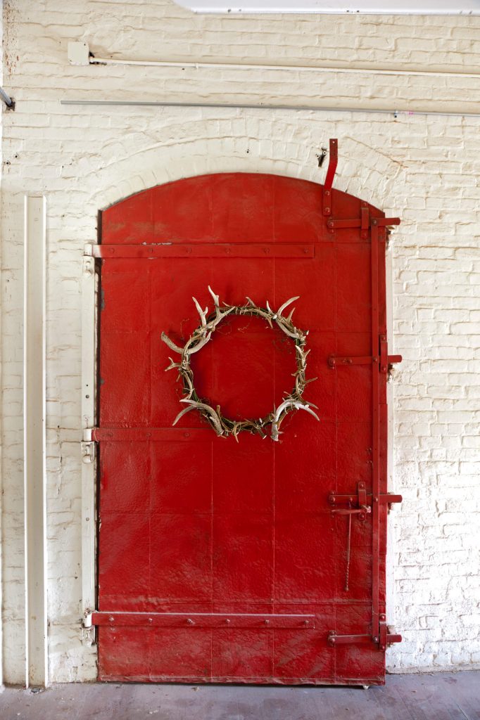 An antler wreath adds just the right texture to this red industrial door.