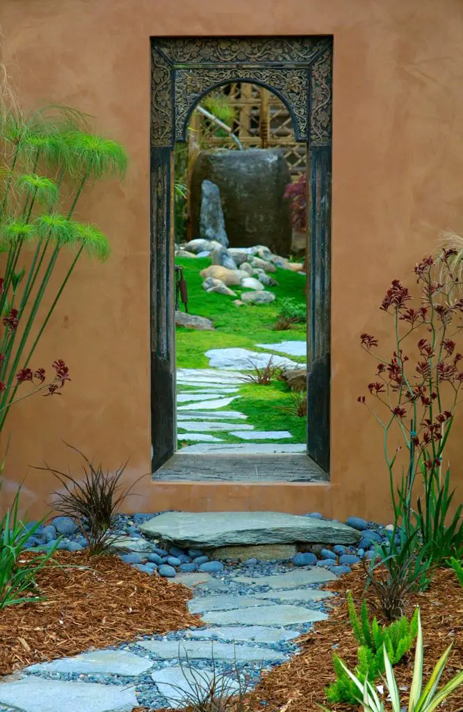 An intricate metal door provides access to a lush garden in Santa Barbara, California