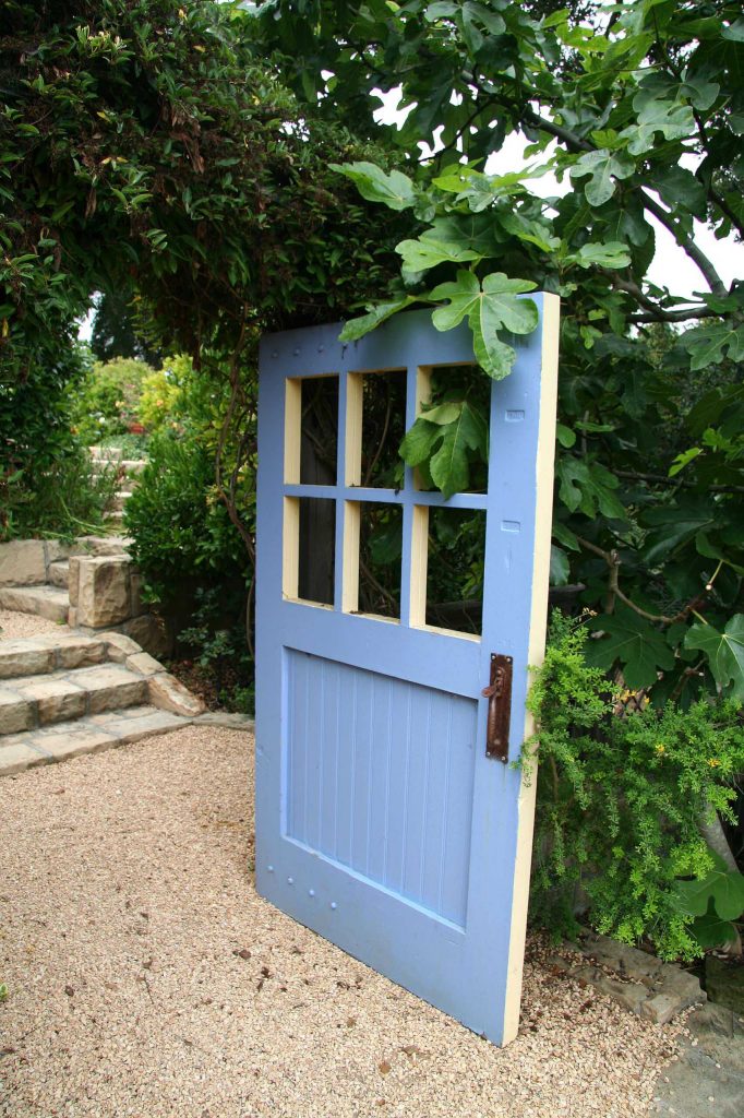 An old painted door with its windows removed welcomes visitors into this Santa Barbara