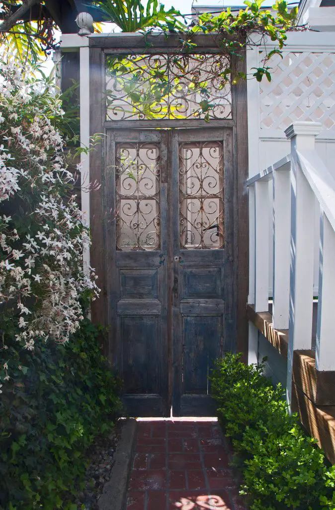 Antique garden doors separate the driveway from the lush garden area of this Los Angeles property.
