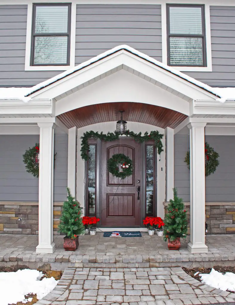 Extra wreaths flank the front door around the light fixtures.