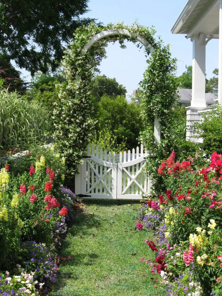 Gated entry to a rear garden with abundant flowers in Wilmington, North Carolina.