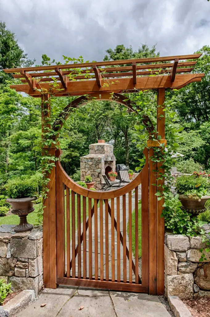 Leafy green vines crawl up the trellised wood gate leading to this New York garden.