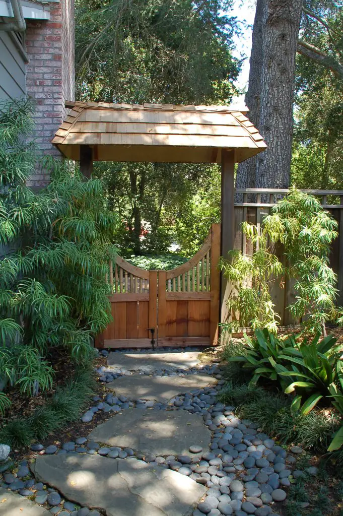 River stones and flagstones blend to make a path leading to an Asian inspired garden gate in Palo Alto, California.