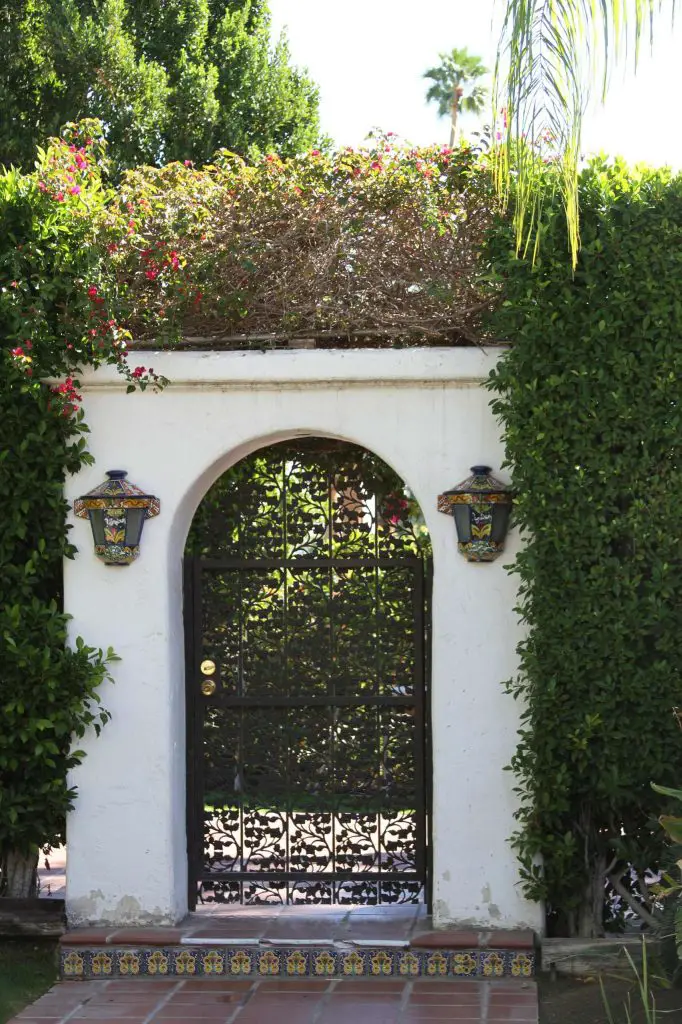 Spanish tiles, white plaster and an intricate wrought iron gate make for a lovely Mediterranean inspired garden gate in Los Angeles.