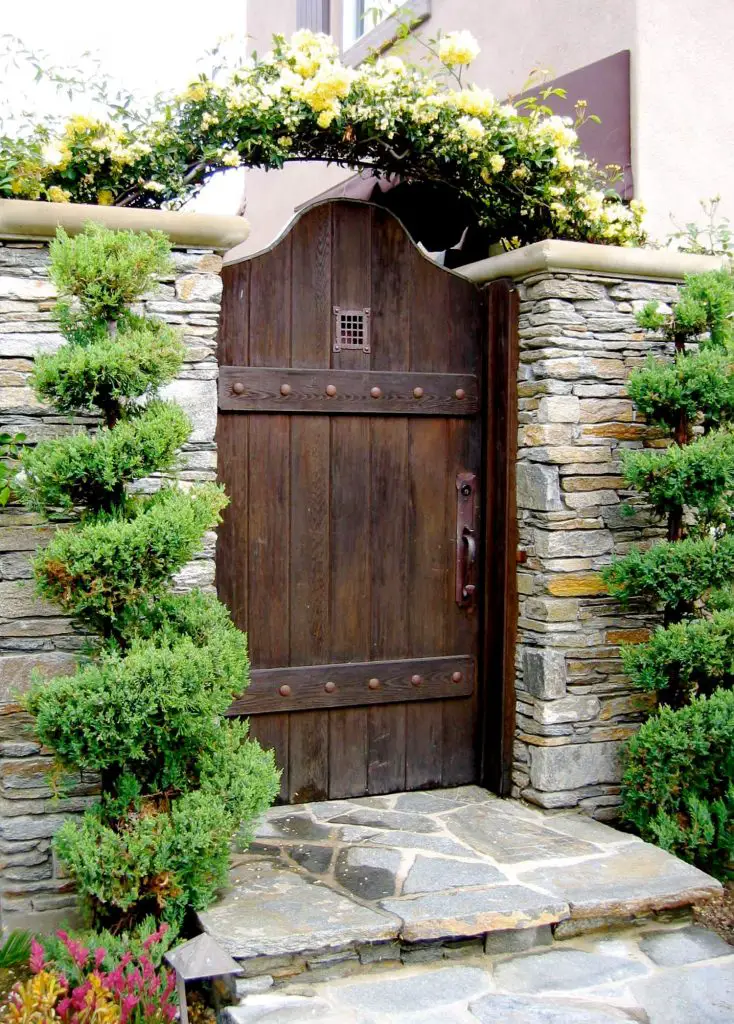 The arbor, stacked stone and topiaries add an inviting feel to this custom made garden gate