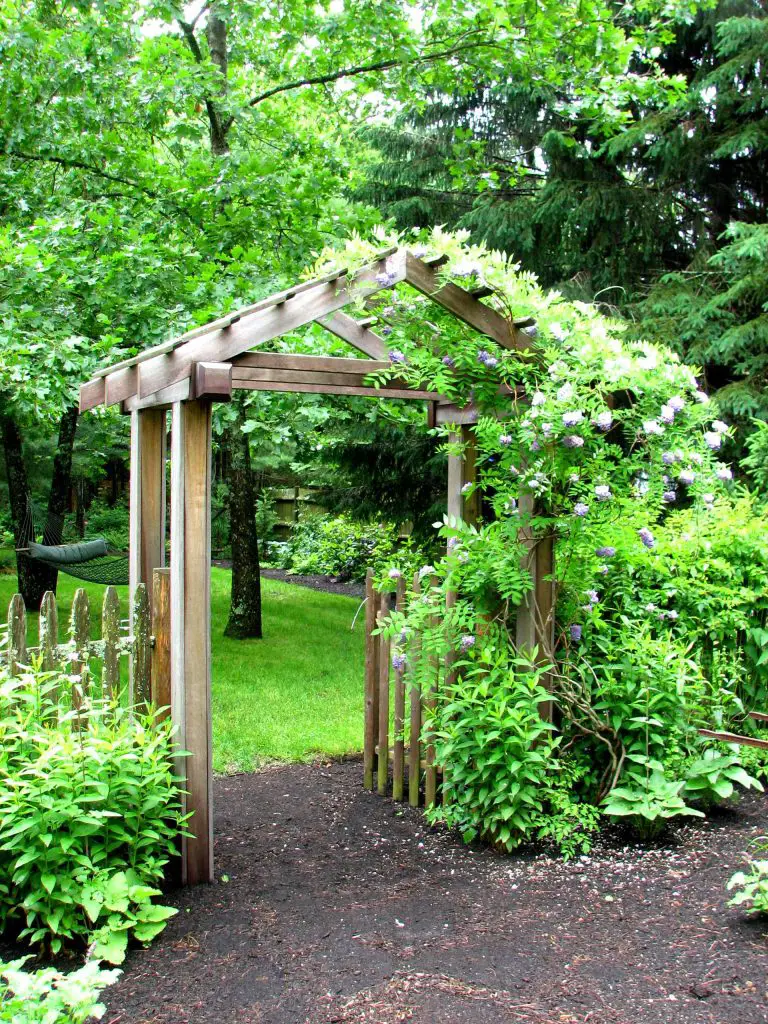 This garden arbor gate and picket fence separate the side yard from the front yard, creating two distinct outdoor areas.