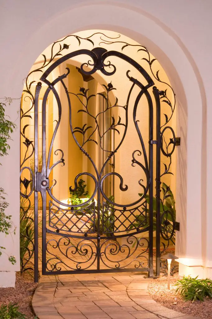 This garden courtyard gate, created by Grizzly Iron Inc., has many forged details, including calla lilies and leaves, scrollwork and a basket weave pattern.